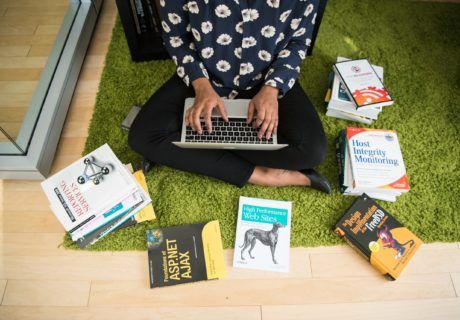 21st Century Skills for Students woman typing on laptop surrounded by books on tech